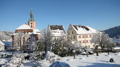 Verschneite alte Gebäude und Kirche bei klarem Himmel im Winter