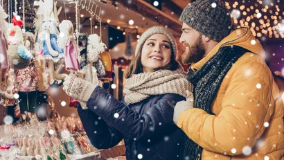 Paar kauft handgemachte Puppen auf einem verschneiten Weihnachtsmarkt