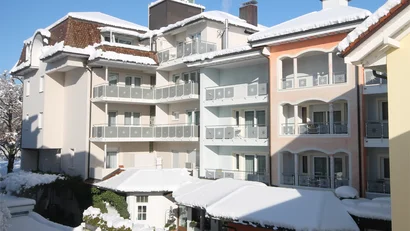 Mehrstöckiges Wohngebäude mit Schnee auf den Dächern und klar blauem Himmel