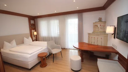 Helles Hotelzimmer mit Doppelbett, Sitzbereich, Holztisch und Wandfernseher