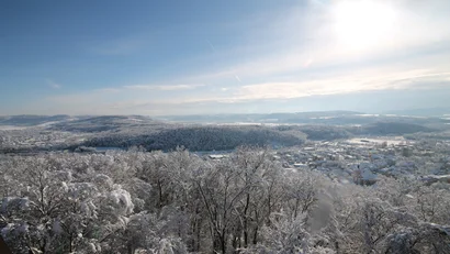 Winterlandschaft mit schneebedeckten Bäumen und Stadt unter hellem Sonnenschein